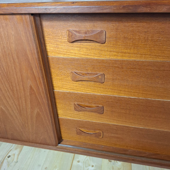 Dettaglio cassettiera centrale in teak con maniglie scolpite.