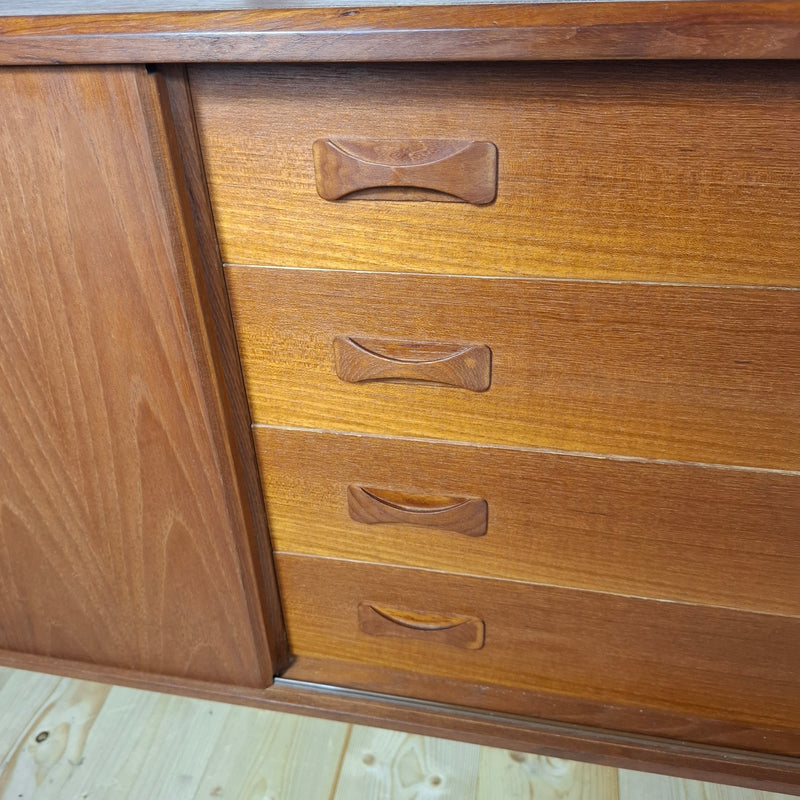 Dettaglio cassettiera centrale in teak con maniglie scolpite.